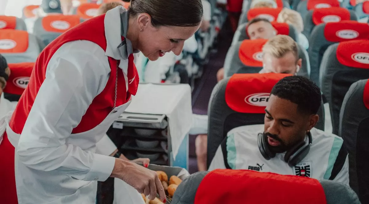 Stewardesa Austrian Airlines oferă o porție de mâncare unui pasager
