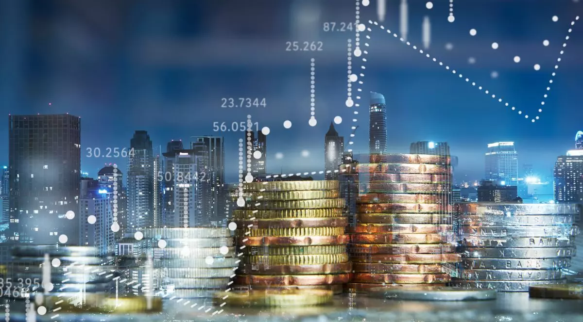 Dublă expunere a unei stive de monede aurii și argintii, cu grafic, iar în spate este un peisaj urban nocturn