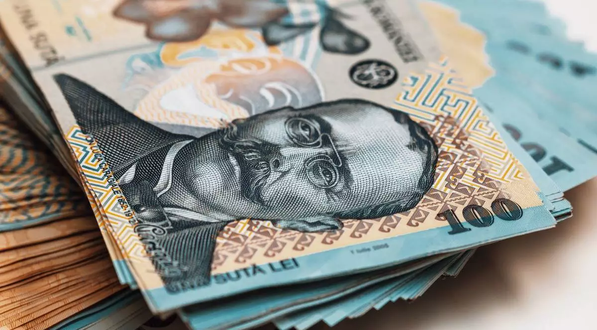 Zeci de hârtii de 100 de lei întinse pe o masă