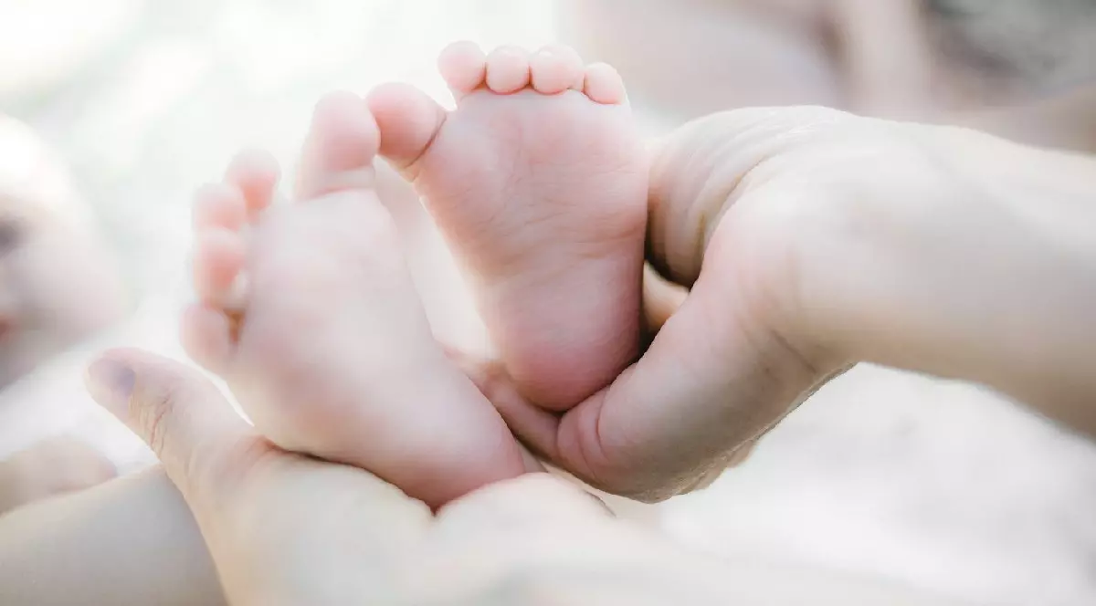 O mamă ține în mâini călcâiele unui bebeluș