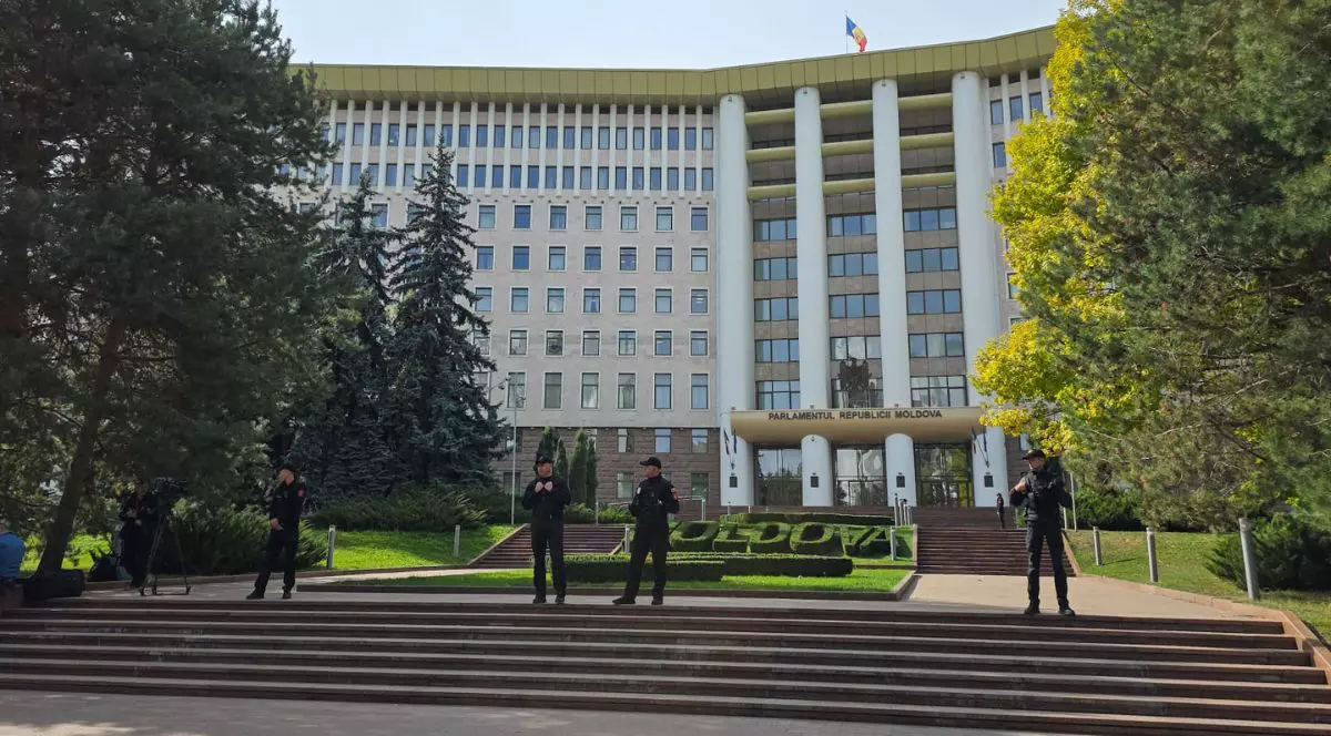 Clădirea parlamentului din Republica Moldova, înconjurată de patru jandarmi, care stau pe scările din fața clădirii. în spatele lor se vede un gard viu aranjat în forma literelor care formează cuvântul „Moldova”, Chișinău, 29 septembrie 2025