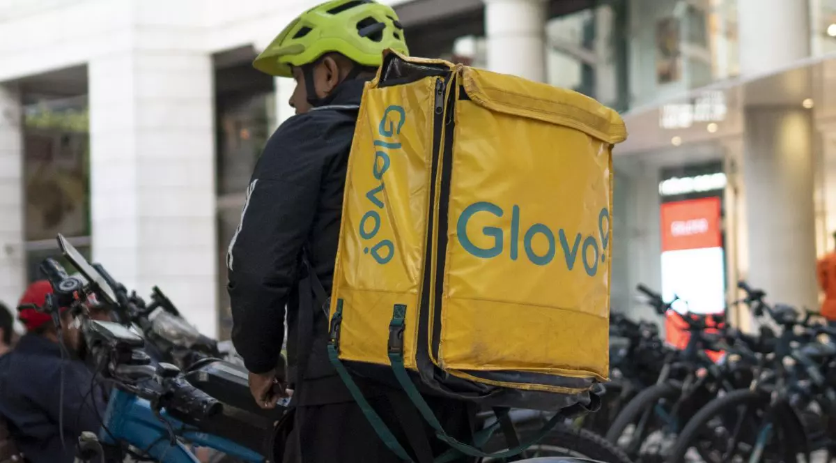 Un livrator cu rucsac Glovo, lângă mai multe biciclete