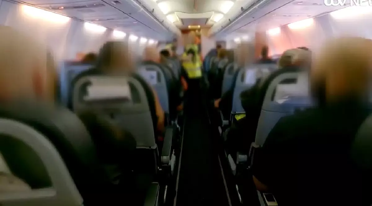 Imagini din avionul in care sunt deportati infractori români din Marea Britanie. Se văd scaunele și vestele galben fosforescent ale polițiștilor