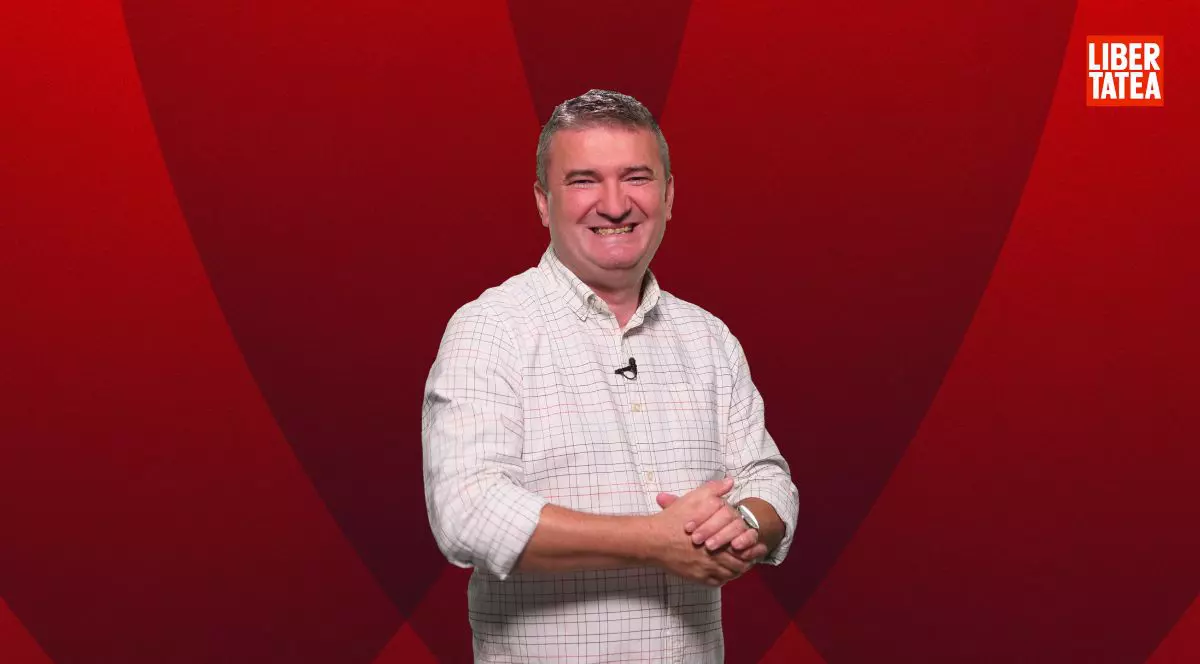 Dorin Chioțea, îmbrăcat într-o cămașă albă, cu mâinile împreunate, pe un fundal de culoare roșu închis și logo-ul Libertatea în dreapta-sus