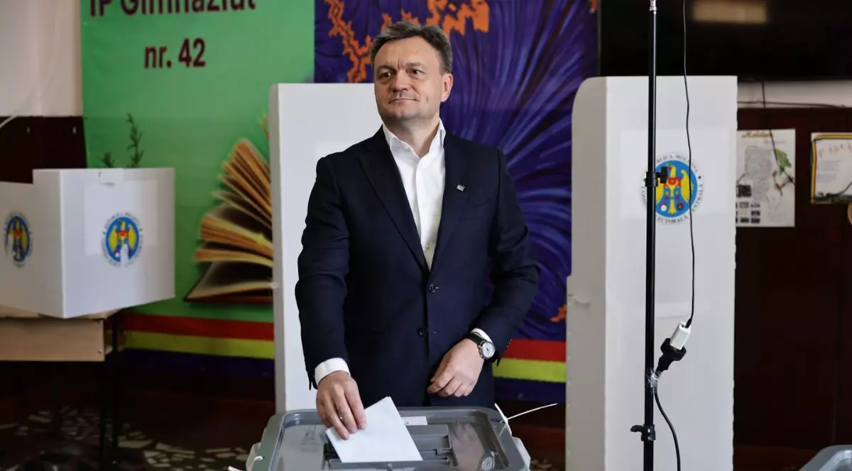 Dorin Recean, îmbrăcat într-un costum negru și o cravată albă, introducând un vot într-o urnă transparentă la alegerile parlamentare din Republica Moldova, 28 septembrie 2025, Chișinău