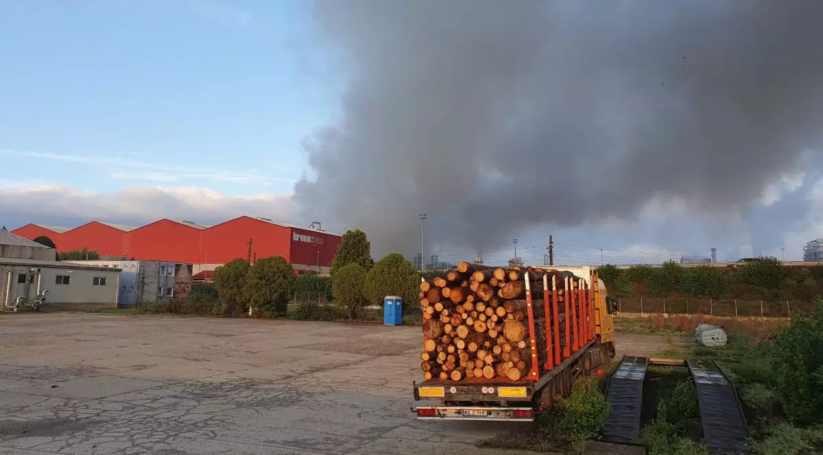 In imagine se vede un camion incarcat cu lemne iar in departare fum gri care se ridica, Sebeș, România, 1 septembrie 2025
