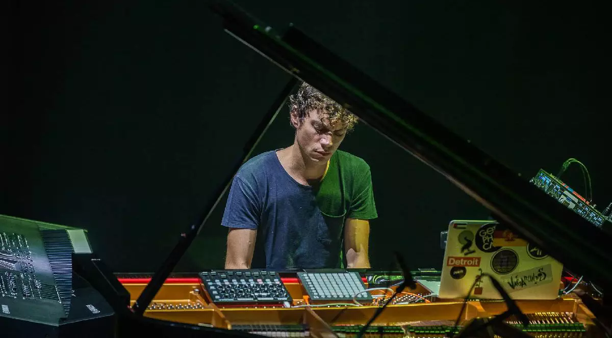 Francesco Tristano, îmbrăcat într-un tricou albastru, mixează muzică într-un studio