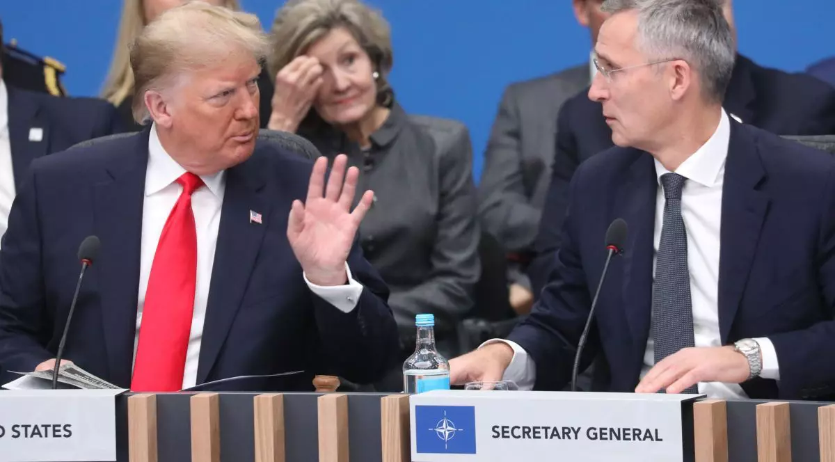 Donald Trump ridică mâna stângă, în timp ce discută cu Jens Stoltenberg, 4 decembrie 2019