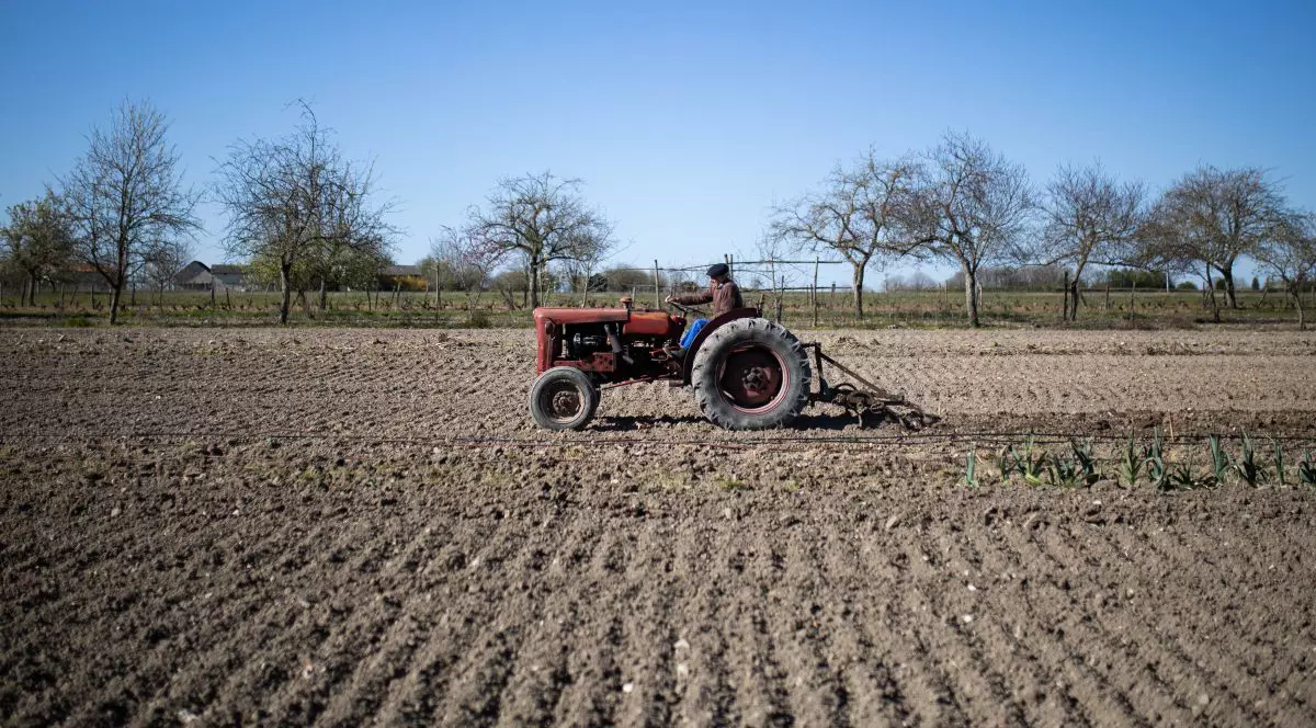 Un bărbat ară cu un tractor un câmp, martie 2021