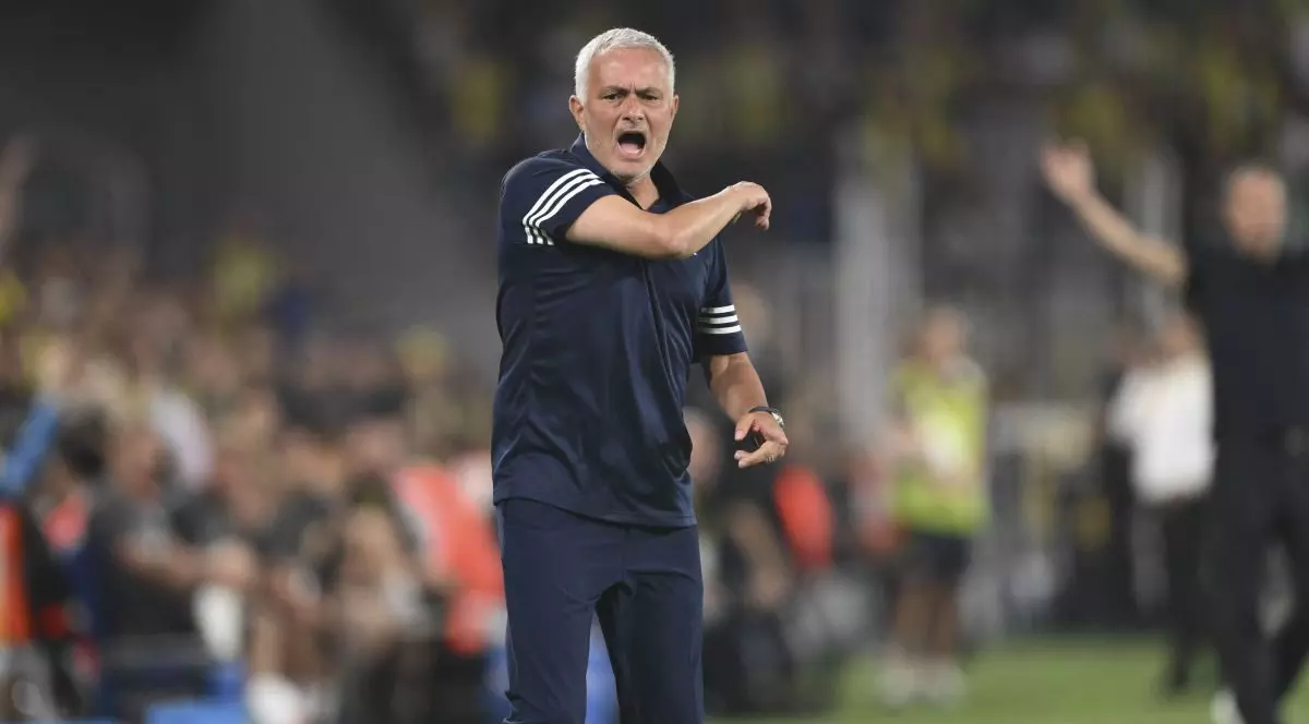 Jose Mournho, înbrăcat într-un tricou negru cu insrții albe, gesticulează cu mâna dreaptă, în timp ce se răstește la jucători de pe marginea terenului, august 2025