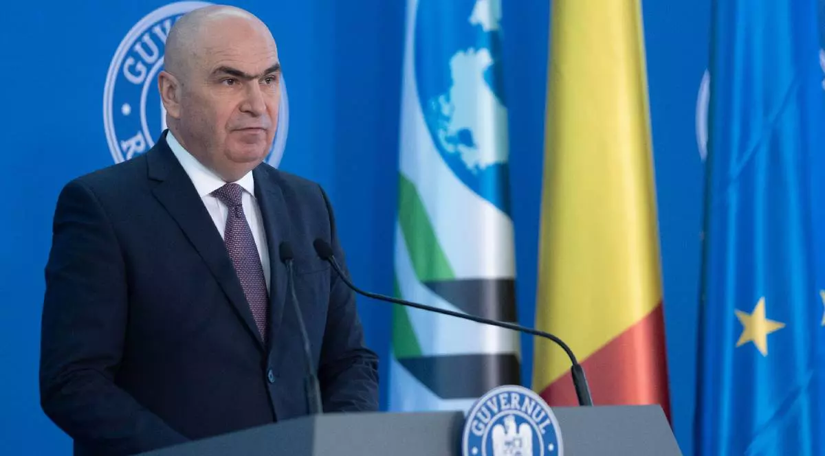 Premierul Ilie Bolojan stă în fața unui pupitru pe care scrie Guvernul României, pregătit să răspundă întrebărilor ziariștilor