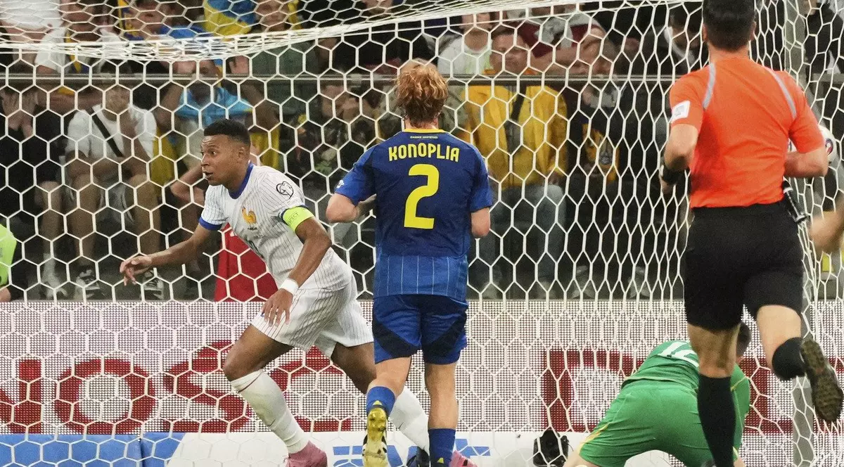 Aatacantul francez Kylian Mbappe, stânga, intr-un echipament alb cu dungi albastre,sărbătorește după ce a marcat al doilea gol al echipei sale în timpul meciului de calificare la Cupa Mondială FIFA 2026 dintre Ucraina și Franța, disputat vineri la Tarczynski Arena din Wroclav, Polonia. In imagine, cu spatele, se vede fotbalistul ucrainean Konoplya