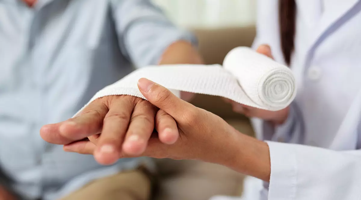 Un doctor care bandajează mâna unui bărbat