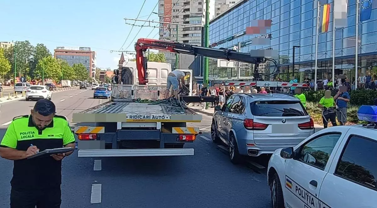 Imagine cu un polițist (stânga) și o mașină care se pregătește să ridice un BMW gri, în Brașov