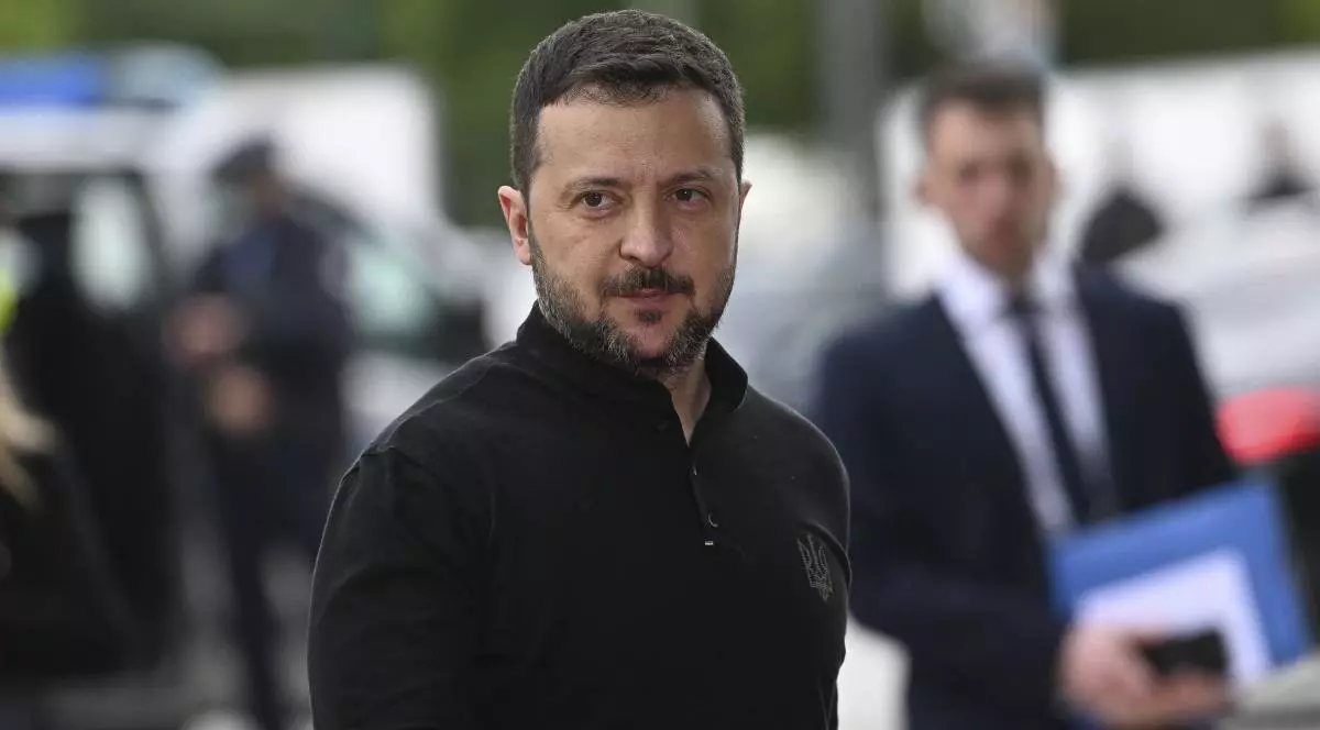 Președintele Ucrainei, Voloimir Zelenski, în timpul unei vizite oficiale, poartă un hanorac negru i zâmbește în fața camerei