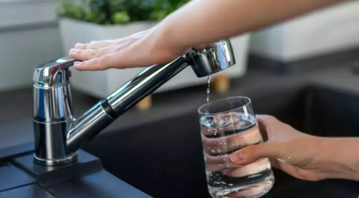 O persoană care umple un pahar cu apă de la robinet