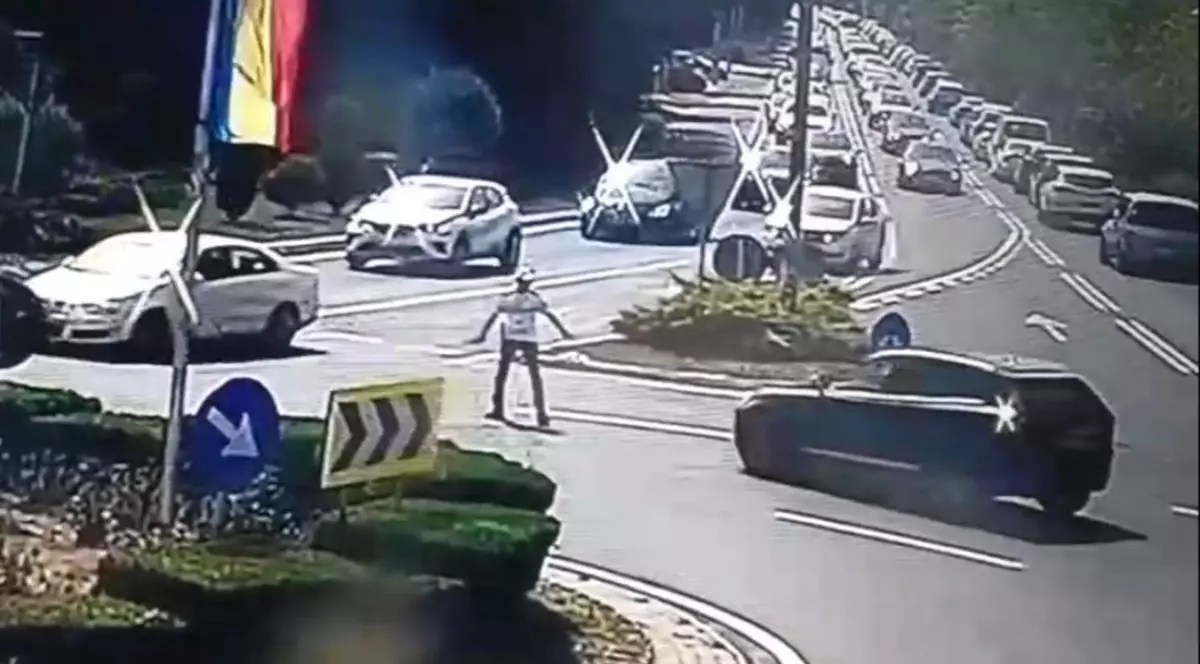 Imagine de pe o cameră de supraveghere cu polițistul aflat în sensul giratoriu și mașina patronului din Arad, de culoare neagră