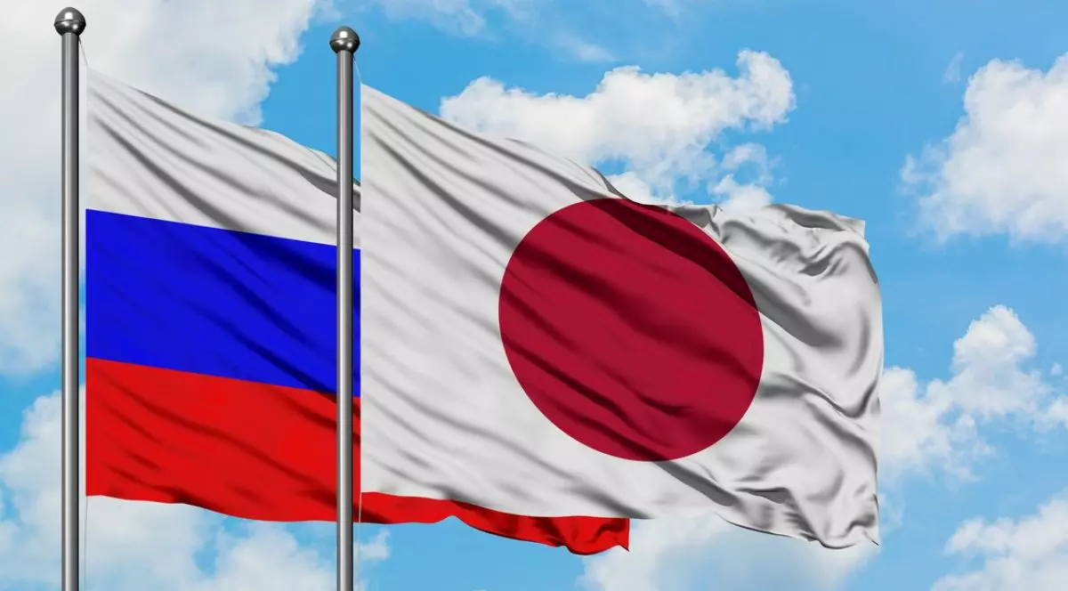Steagurile Rusiei și Japoniei fluturând în vânt pe un cer albastru înnorat. Concept de diplomație, relații internaționale.