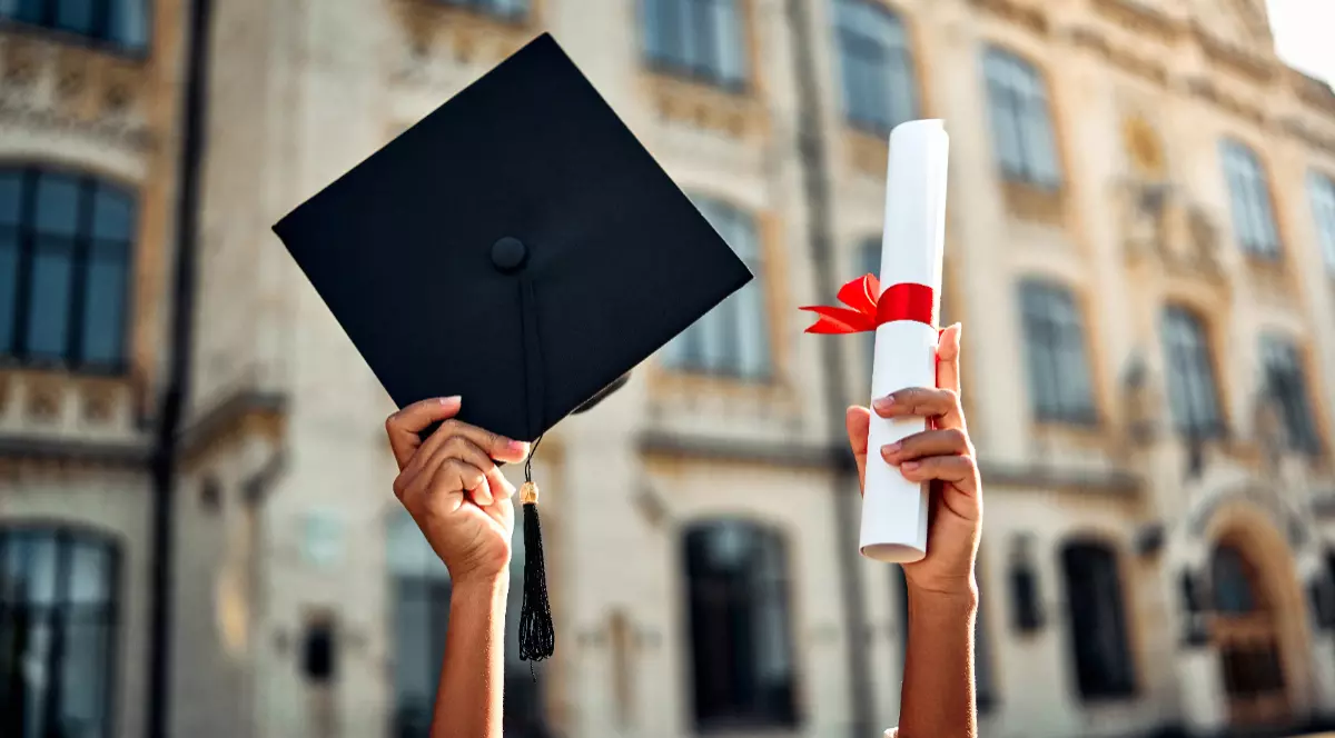 O persoană care ține în mâini toca și diploma de absolvire