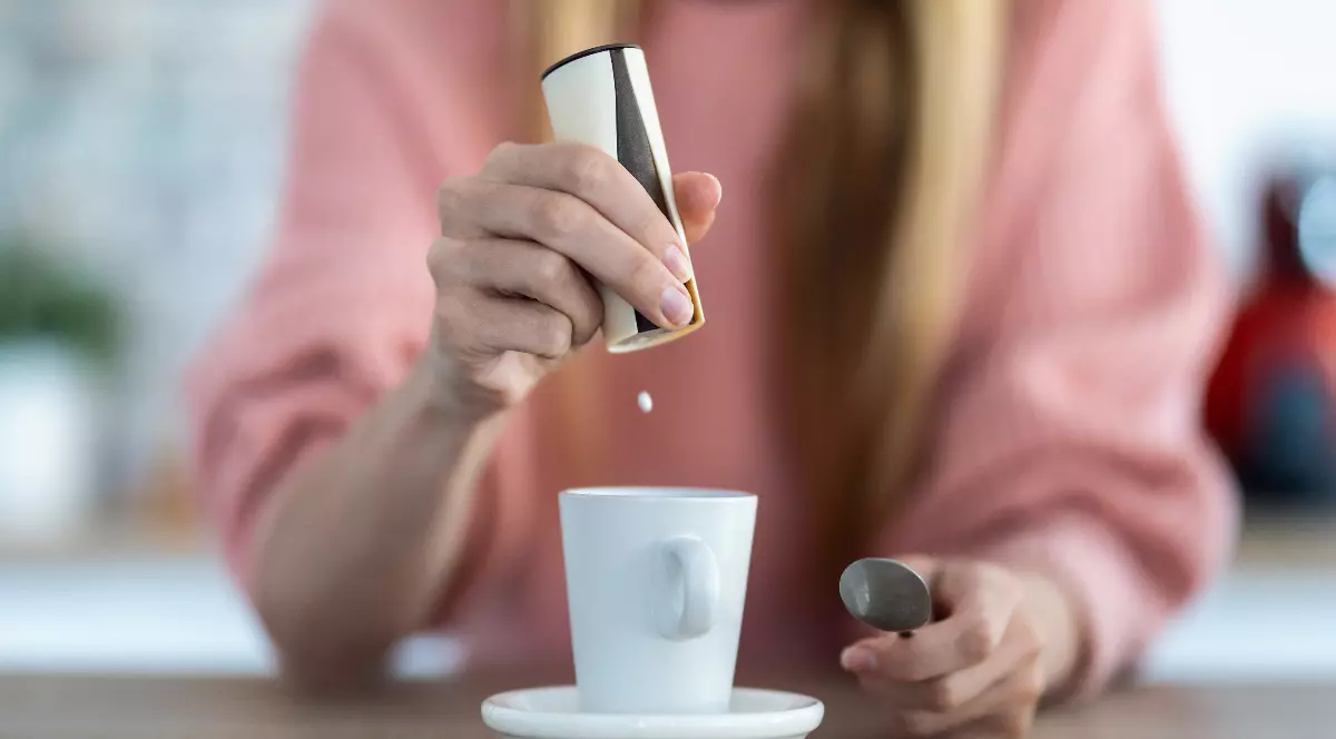 O femeie care pune zaharină în cafea