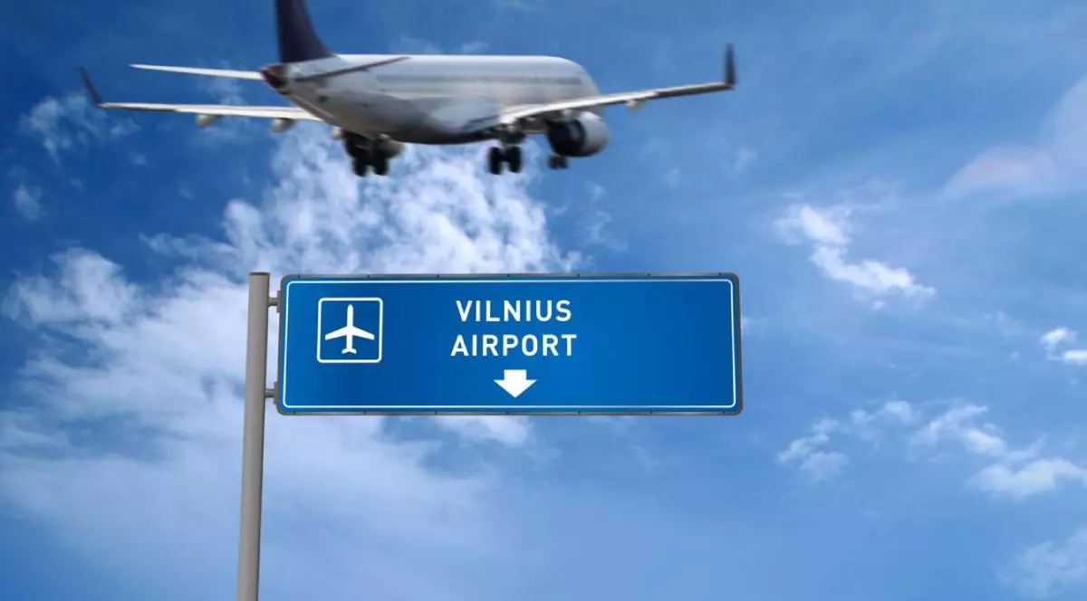 Imgagone cu un avion care sboara deasupra unui semn albastru cu Aeroportul Vilnius