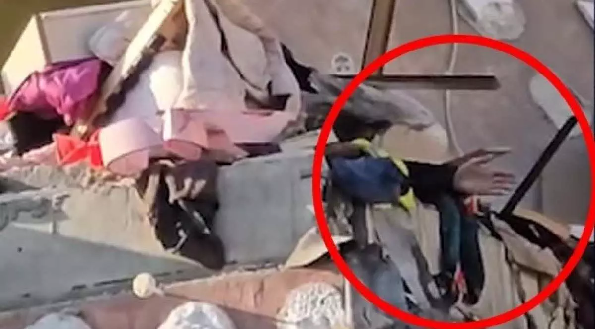 Un bărbat, prins sub dărâmături, strigă după ajutor și face cu mâna pentru a fi văzut de salvatori