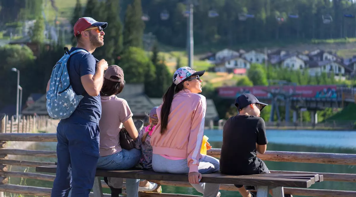 Familie cu 2 copii, un baiat si o fata. Stau pe banca intr-o zona de munte cu lac