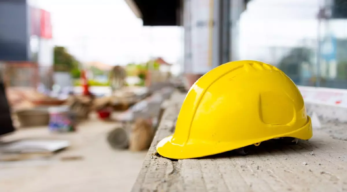 Cască de protecție galbenă atârnată pe șantier, reprezentând ingineria, munca calificată și măsurile de siguranță industrială