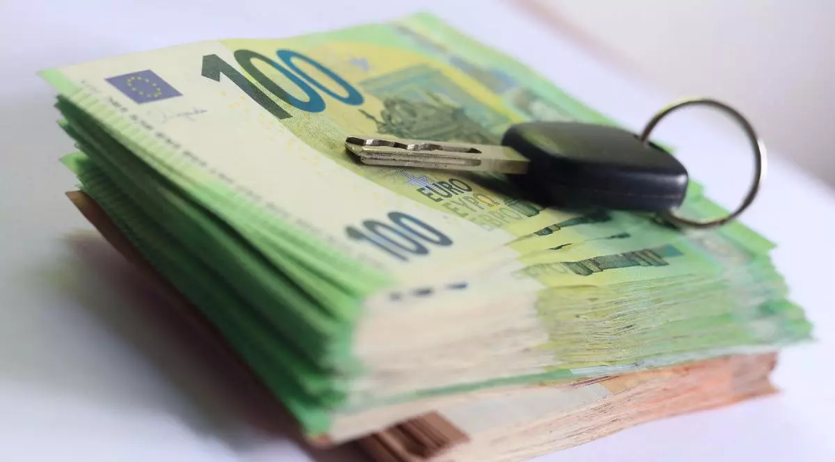 Cheie de mașină peste un teanc de bani format din bancnote de 100 și 50 de euro