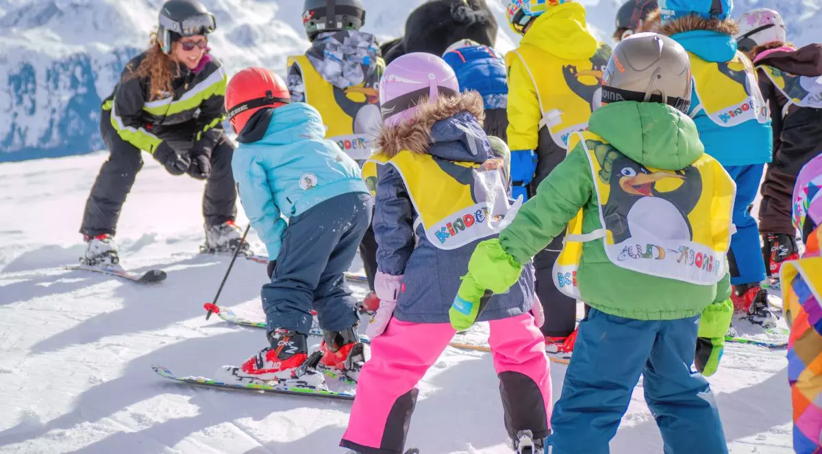 copii pe partie la schi alaturi de un instructor de schi