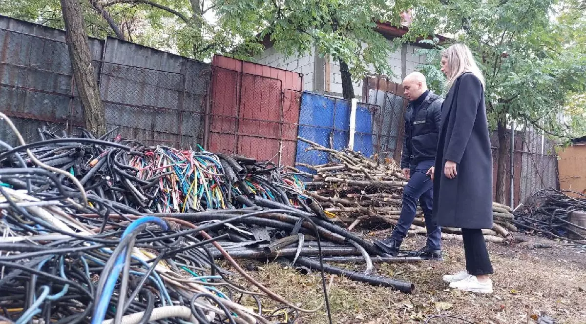 Diana Buzoianu, cu palton negru, alături de un bărbat îmbrăcat în negru, în control la Sintești, unde se uită la niște cabluri - 15 octombrie 2025