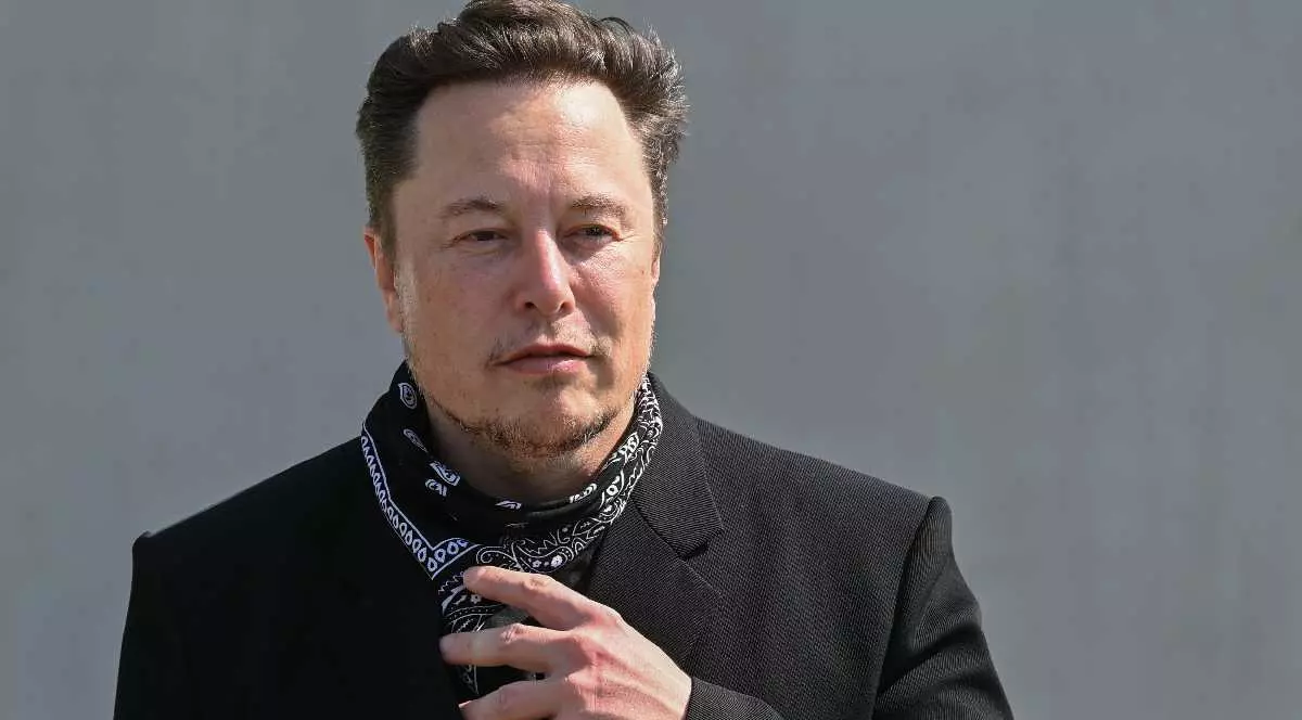 Elon Musk îmbrăcat cu palton și având un fular la gât