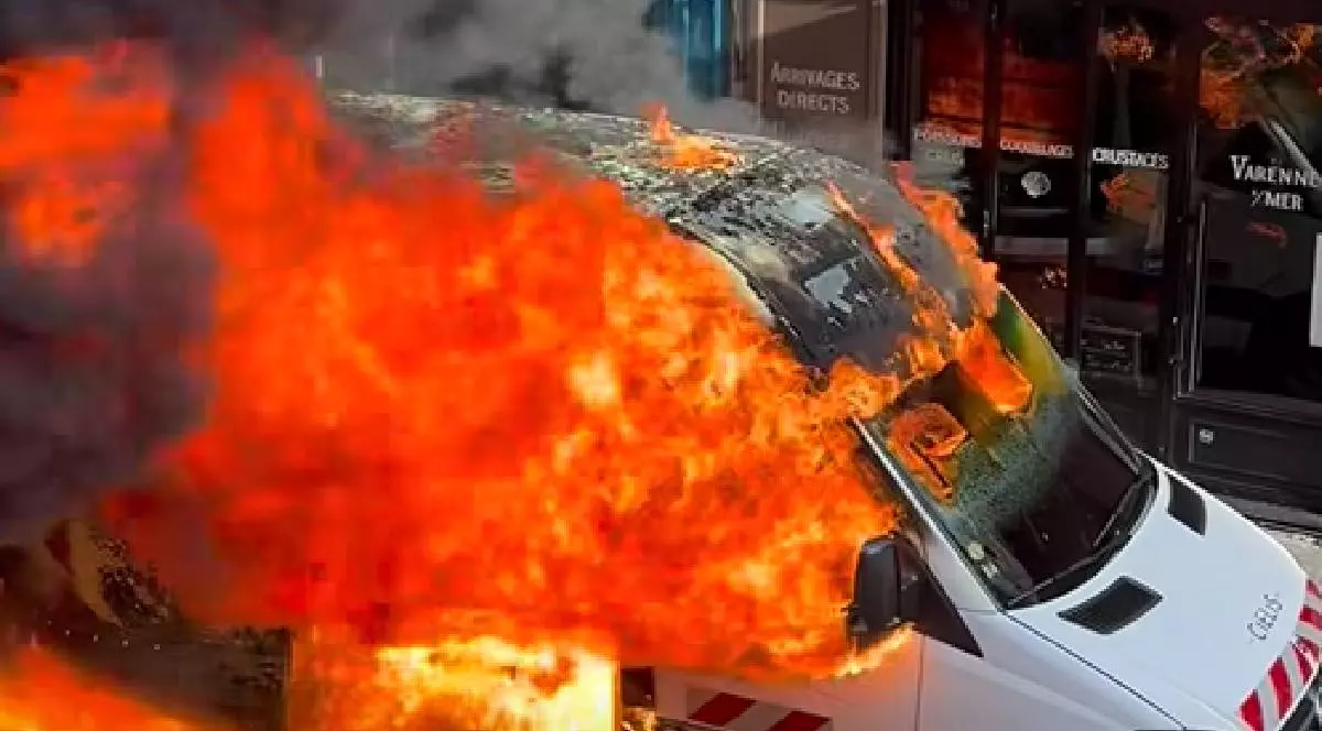 În imagine o dubă albă arde în flăcări pe o stradă centrală din Paris