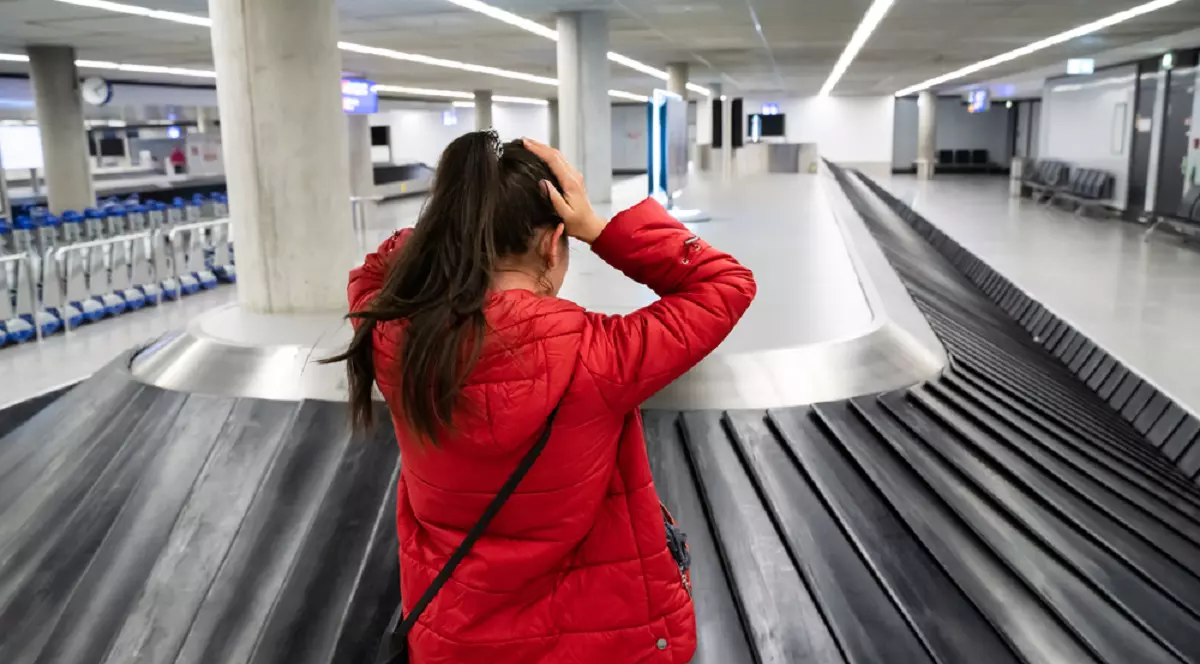 Ce faci dacă ţi s-a pierdut bagajul în timpul unei călătorii cu avionul - Imagine cu o femeie care şi-a pus mâinile în cap în faţa caruselului de bagaje dintr-un aeroport