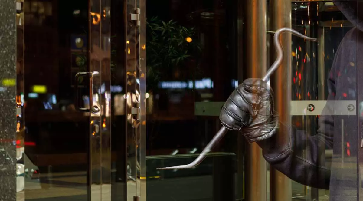 Bărbat cu un levier în mână sparge geamul unui magazin