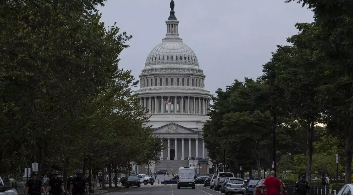 Capitoliul SUA, în Washington, DC, pe 30 septembrie 2025. Cladirea guvernului, vazute in capatul unei alei marginita de pomi, masini si oameni pe strada. Guvernul federal s-a închis la miezul nopții,