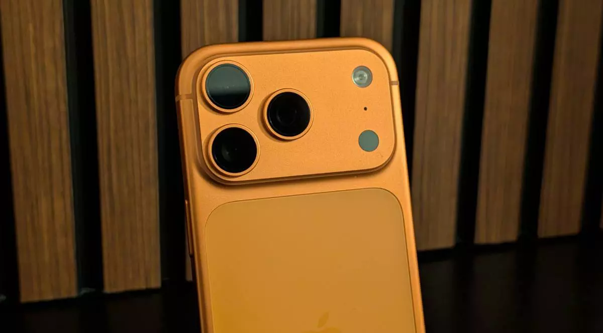 Platoul camerei foto a lui iPhone 17 Pro, de culoare portocalie, pe un fundal de lemn.