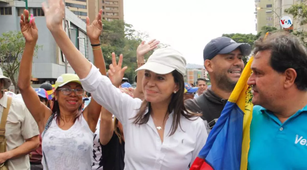 Maria Corina Machado, castigatoarea Premiului Nobel pentru Pace 2025, in strada, in multime, surprinsa in timp ce face cu mana oamenilor, purtand i camasa alba si o sapca tot alba