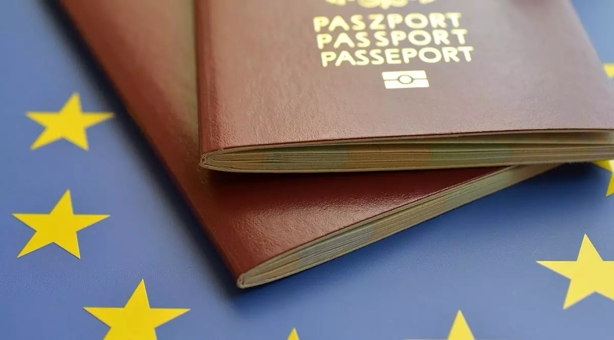 Două pașapoarte cu coperta maro, unul peste altul, care stau pe steagul Uniunii Europene, de culoare albastră cu stele de culoare galbenă