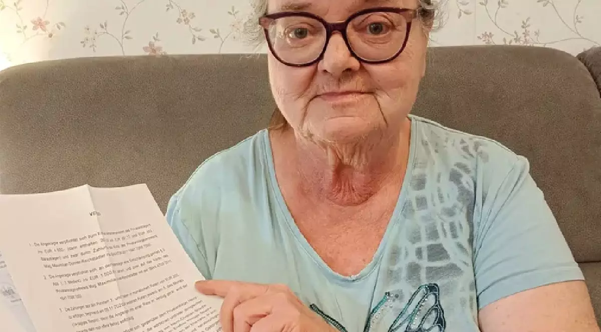 O femeie in varsta, cu ochelari, imbracata intr-un tricou albastru, tine in mana o hartie