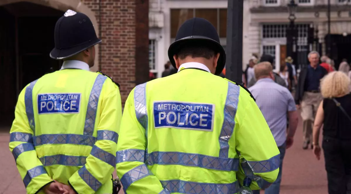 Doi polițisti britanici, in uniforma, fotografiati de la spate, pe strada