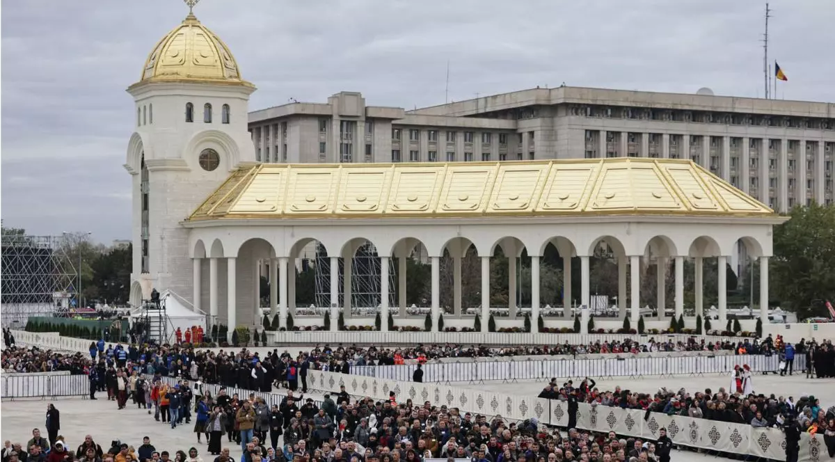 Ceremonia de sfințire a picturii Catedralei Mântuirii Neamului. In curtea catedralei oamenii sunt organizati si stau in grupuri in zone special amenajate intr-o ordine care impresioneaza