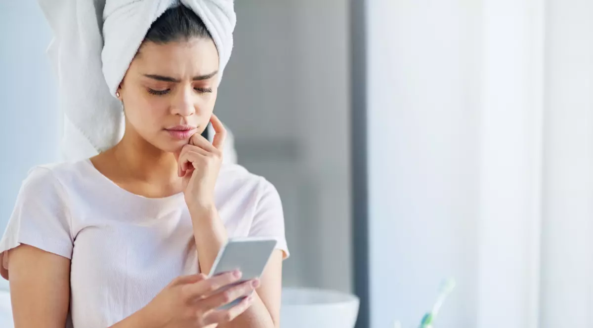 O tânără care ține un telefon în mână, în baie