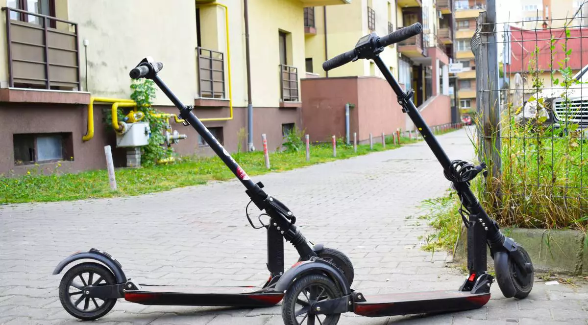 Două trotinetele electrice „parcate” la intrare pe trotuar lângă un bloc de locuințe din Cluj