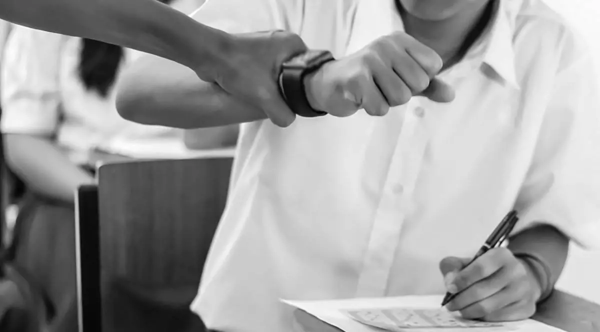 Cdru strans, amb negru, cu mana unei femei care strange mana unui elev cu un smart watch , in clasa, in timpul unui examen. Conceptul de abuz la scoala