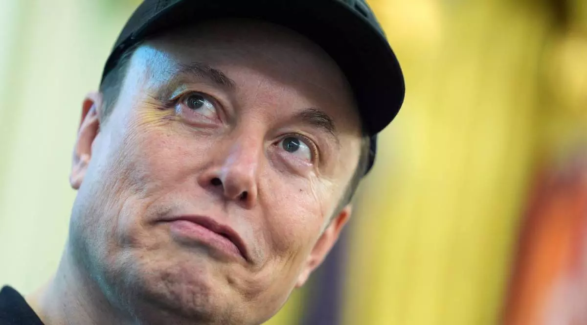 Elon Musk, cu o șaptă neagră în cap și un hanorac negru, fotografiat tip portret în timp ce zâmbește și privește în sus. În spatele său se vede draperia galbenă din Biroul Oval