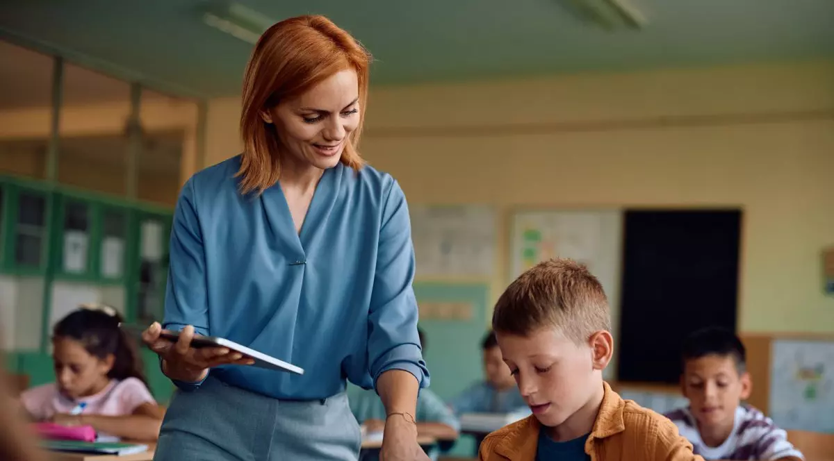 Învățătoare alături de elevi în clasă