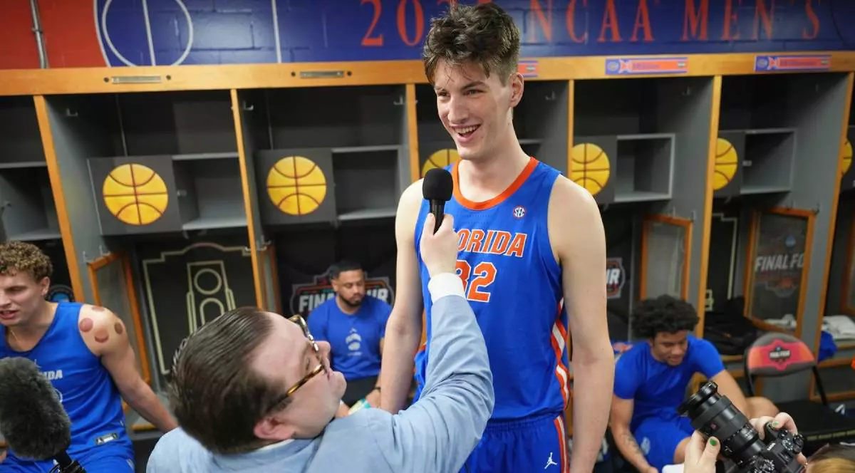 Olivier Rioux, jucătorul de baschet de 19 ani care are 2,36 metri înălțime, în timp ce acordă un interviu. Tânărul este atât de înalt, în cât reporterul abia reușește să îi țină microfonul