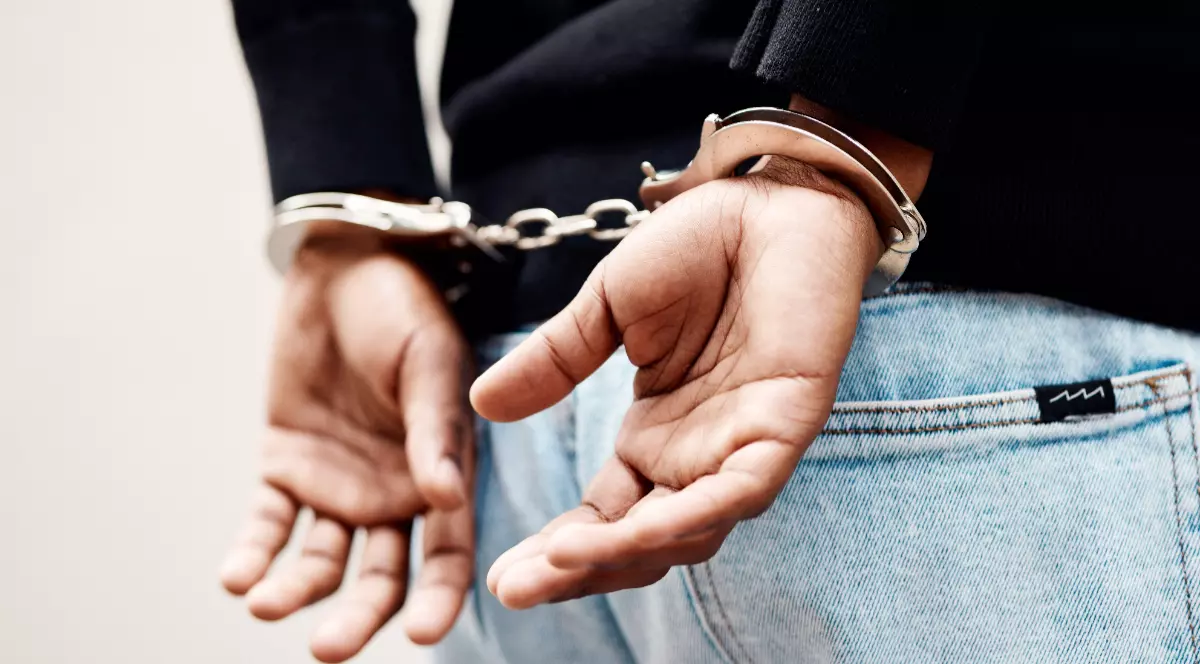 O persoană care are mâinile la spate, cu cătușe.