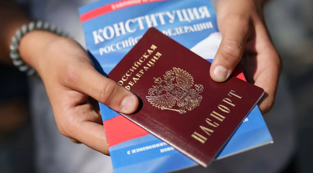 O persoană ține în mâini un pașaport rusesc și o versiune tipărită a Constituției Rusiei, august 2025